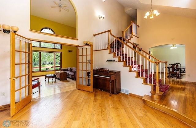 interior space featuring high vaulted ceiling, hardwood / wood-style floors, french doors, and ceiling fan with notable chandelier