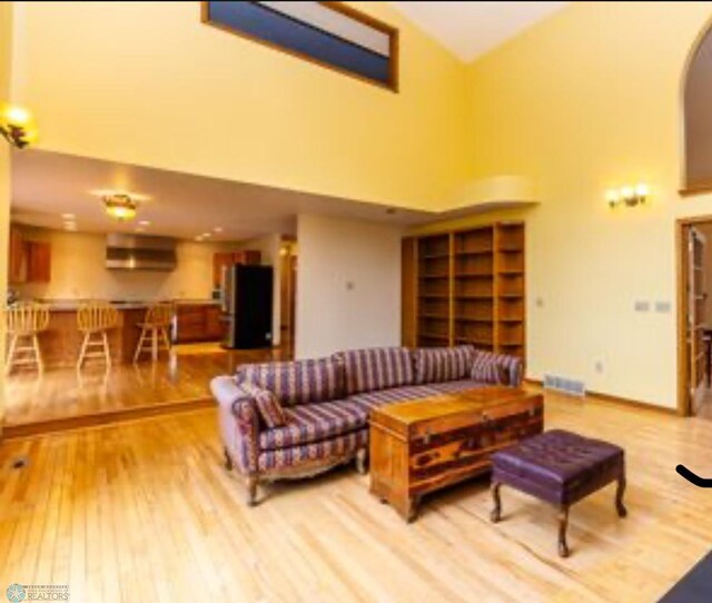 living room with high vaulted ceiling and light wood-type flooring