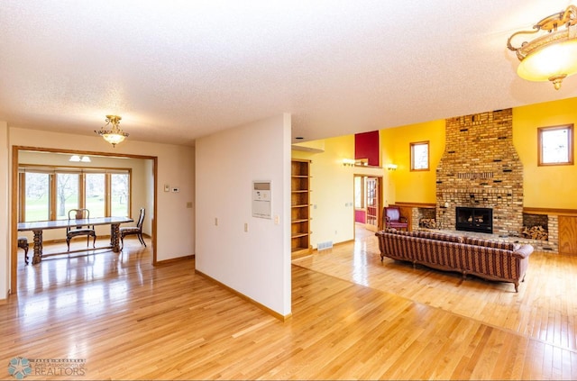 living room featuring a textured ceiling, a fireplace, brick wall, and wood-type flooring