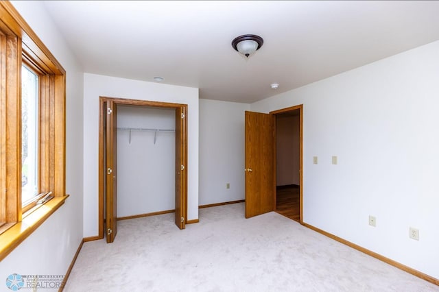 unfurnished bedroom with multiple windows, a closet, and carpet flooring