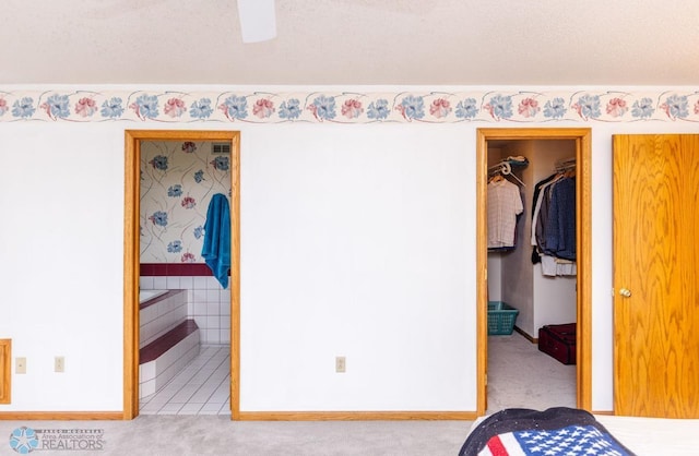 unfurnished bedroom with a walk in closet, a closet, ceiling fan, and carpet floors