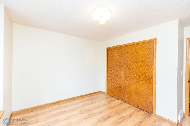 unfurnished bedroom featuring a closet, light hardwood / wood-style floors, and a textured ceiling