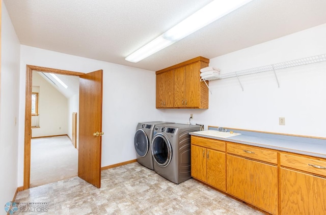 washroom with washer hookup, light colored carpet, sink, washer and clothes dryer, and cabinets