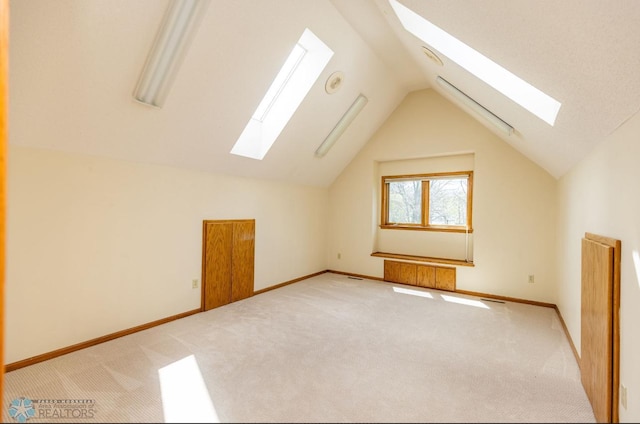 bonus room with vaulted ceiling with skylight and carpet flooring