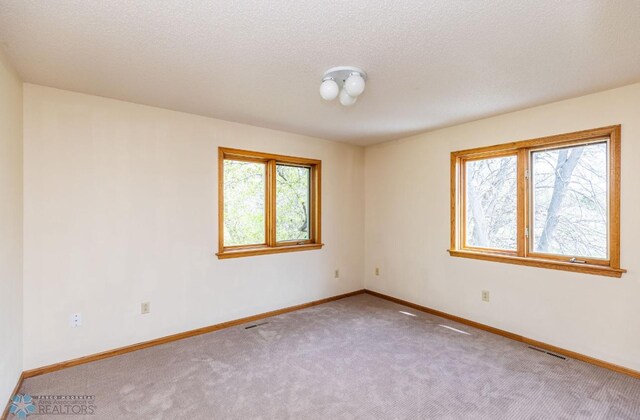 spare room with a textured ceiling and carpet floors