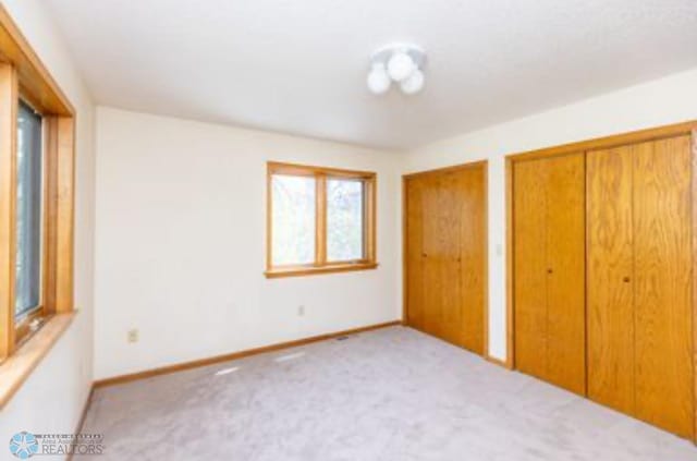 unfurnished bedroom with two closets and carpet floors