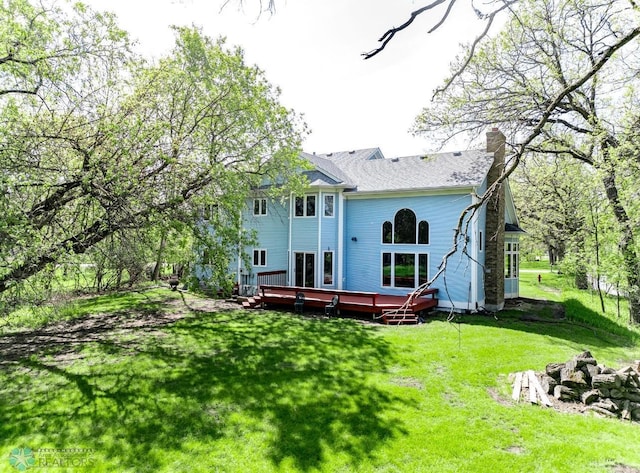 rear view of property with a wooden deck and a yard