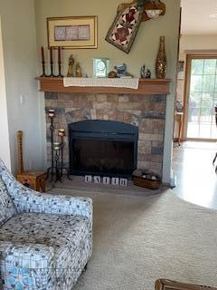 carpeted living room with a stone fireplace