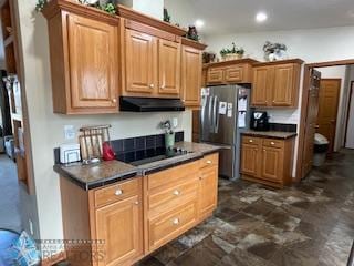 kitchen with stainless steel refrigerator, dark tile floors, and black electric cooktop