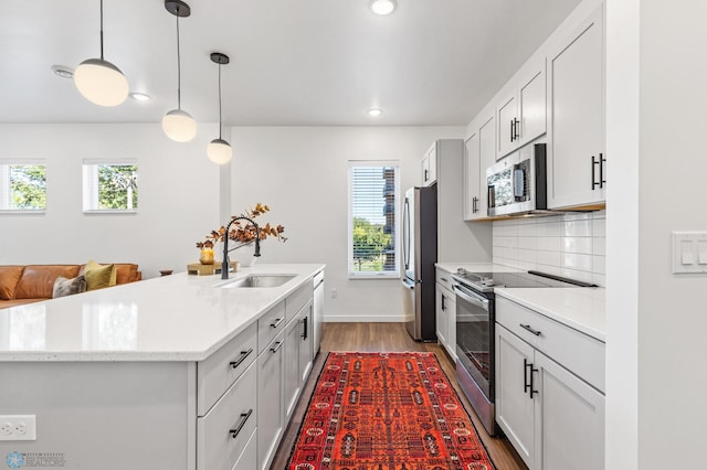 kitchen with pendant lighting, appliances with stainless steel finishes, a healthy amount of sunlight, and sink