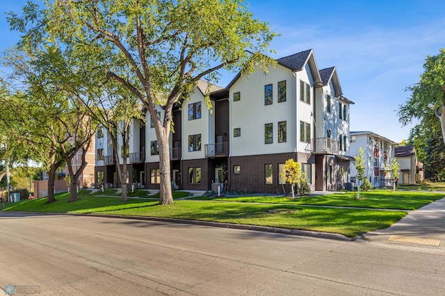 view of front of house featuring a balcony, central AC unit, and a front yard