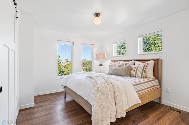 bedroom with dark hardwood / wood-style floors and a barn door