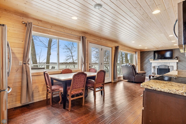 dining space featuring dark hardwood / wood-style floors, plenty of natural light, a brick fireplace, and wooden ceiling