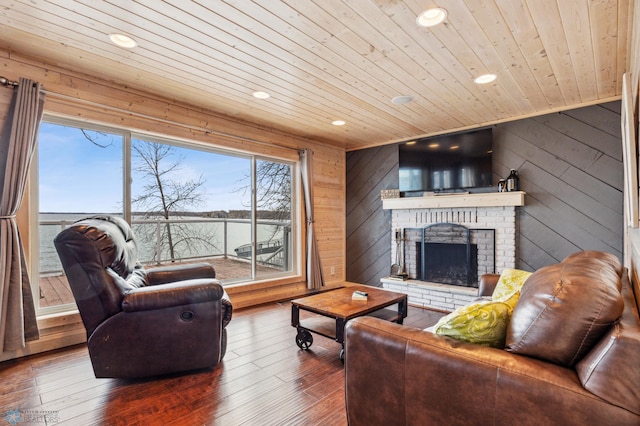 living room featuring dark hardwood / wood-style floors, wood walls, wood ceiling, and a brick fireplace