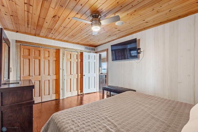 bedroom with multiple closets, dark wood-type flooring, ceiling fan, and wood ceiling