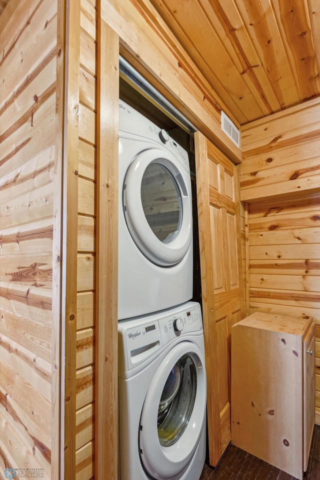 laundry room with stacked washer / dryer, dark wood-type flooring, wooden walls, and wood ceiling