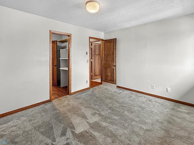 unfurnished bedroom featuring carpet, a walk in closet, a closet, and a textured ceiling