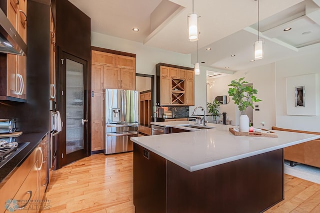 kitchen featuring light hardwood / wood-style floors, a center island with sink, appliances with stainless steel finishes, backsplash, and sink