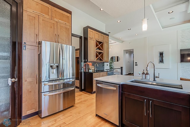 kitchen featuring light hardwood / wood-style floors, stainless steel appliances, backsplash, hanging light fixtures, and sink