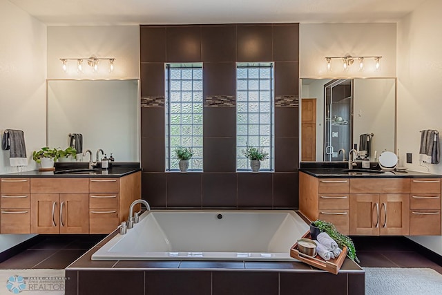 bathroom featuring tiled tub, dual sinks, and large vanity