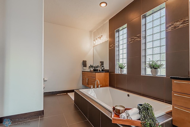 bathroom with tile flooring, tiled tub, and vanity