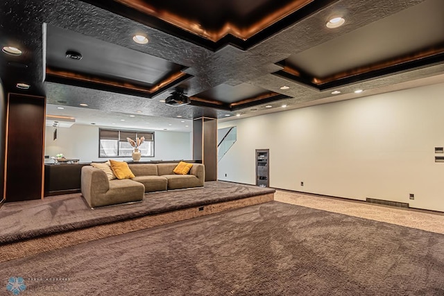 carpeted cinema room featuring a tray ceiling and coffered ceiling