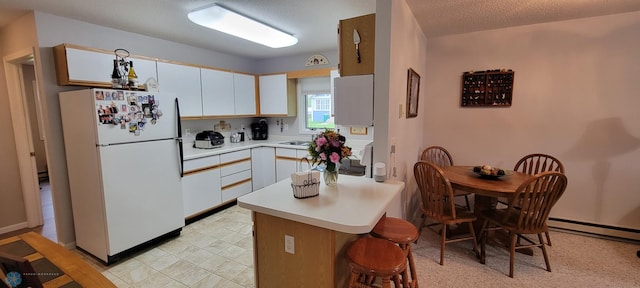 kitchen featuring a textured ceiling, white refrigerator, white cabinets, baseboard heating, and light tile flooring