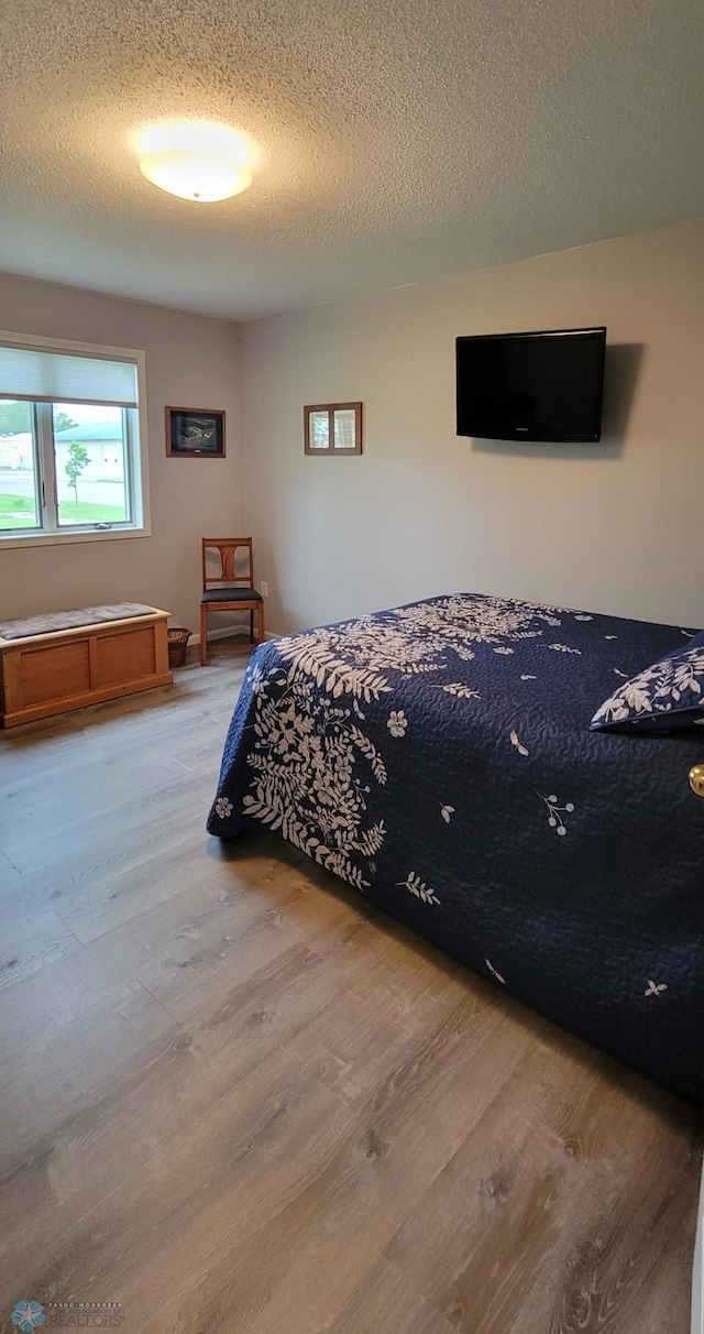 bedroom with a textured ceiling and hardwood / wood-style flooring