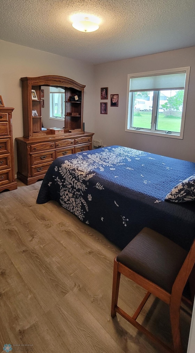 bedroom with a textured ceiling and hardwood / wood-style flooring