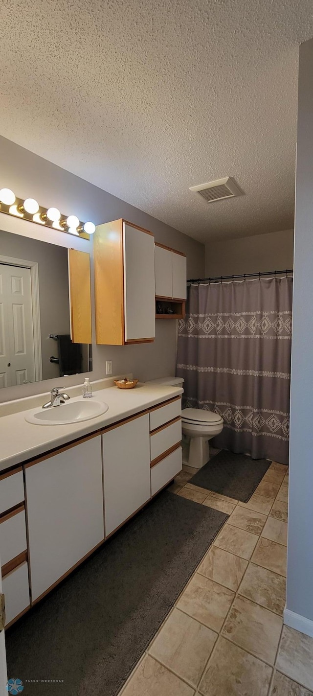 bathroom featuring tile flooring, a textured ceiling, toilet, and vanity