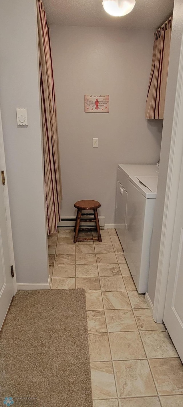 washroom with a textured ceiling, light tile flooring, and washer / dryer