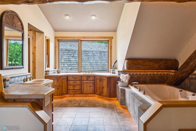 bathroom with tiled bath, plenty of natural light, tile patterned floors, and lofted ceiling