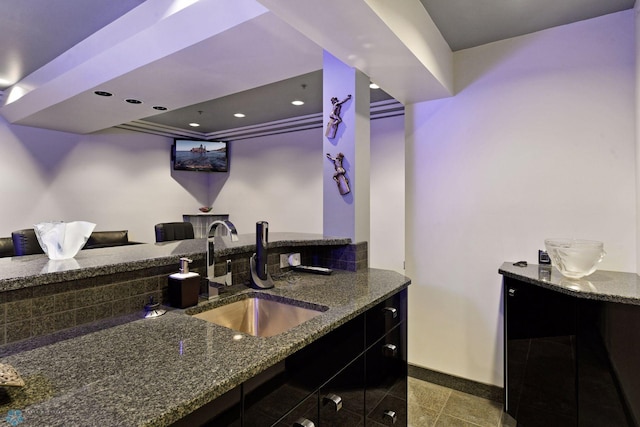 kitchen featuring sink, a tray ceiling, tile patterned flooring, and dark stone counters