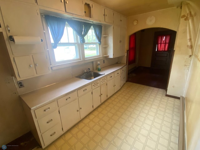 kitchen with sink, white cabinetry, and light tile flooring