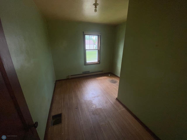 unfurnished room featuring a baseboard radiator and hardwood / wood-style flooring