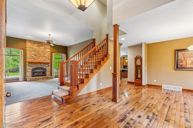 staircase with a textured ceiling, decorative columns, a fireplace, carpet, and ceiling fan