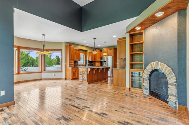 kitchen with a stone fireplace, light hardwood / wood-style floors, and pendant lighting