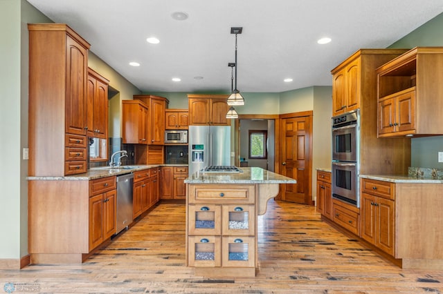 kitchen featuring hanging light fixtures, a center island, stainless steel appliances, and light hardwood / wood-style floors