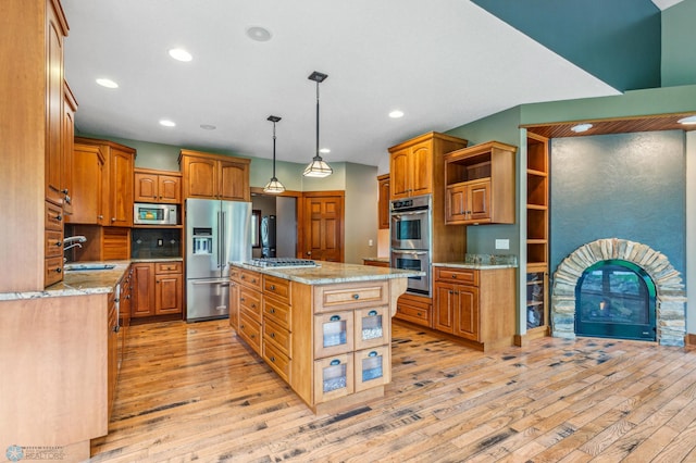 kitchen featuring light hardwood / wood-style flooring, decorative light fixtures, a center island, sink, and appliances with stainless steel finishes