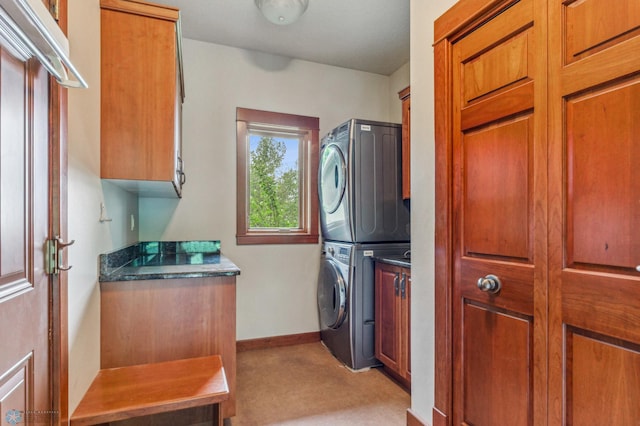 laundry room featuring stacked washer and clothes dryer, light colored carpet, and cabinets