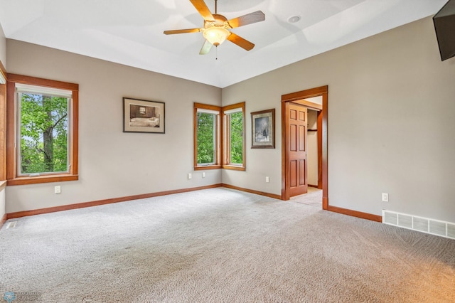 empty room featuring a tray ceiling, carpet, and ceiling fan