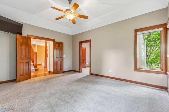 unfurnished bedroom with carpet flooring, ceiling fan, and a tray ceiling