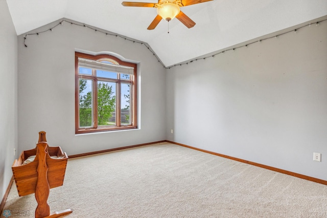 carpeted empty room with vaulted ceiling and ceiling fan