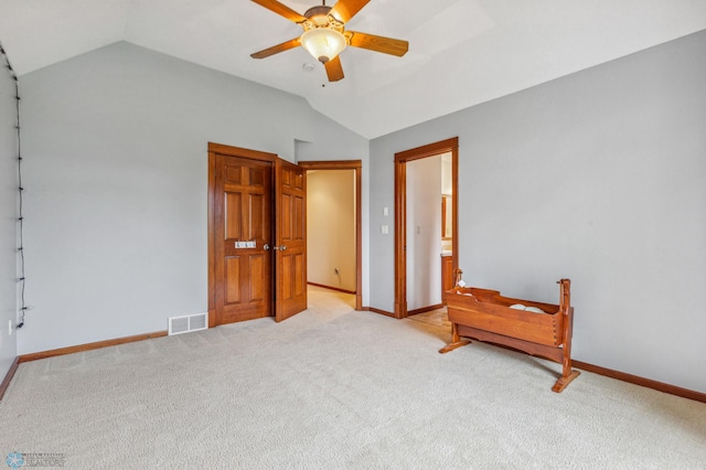 carpeted bedroom with ensuite bathroom, ceiling fan, and lofted ceiling