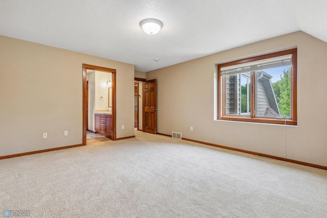 carpeted empty room with vaulted ceiling and a textured ceiling