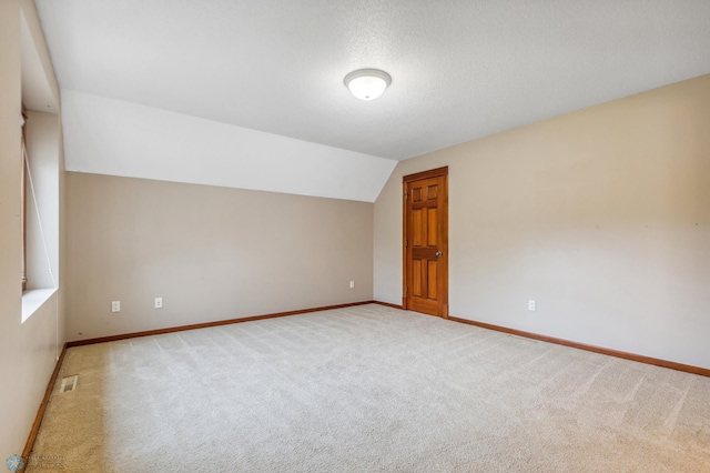 carpeted empty room with a textured ceiling and lofted ceiling