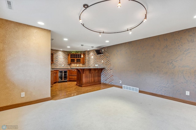 kitchen featuring brick wall, beverage cooler, light colored carpet, a breakfast bar, and pendant lighting