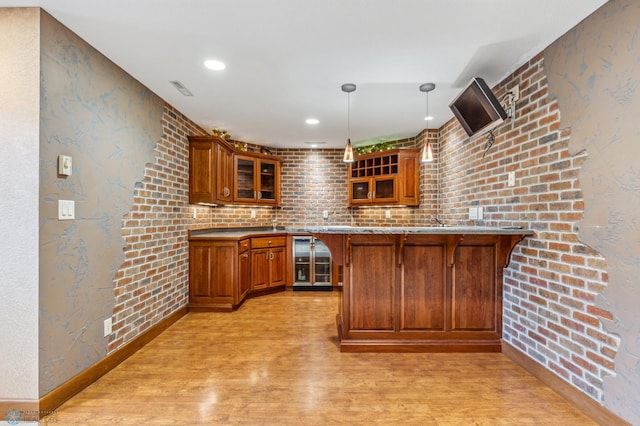 kitchen featuring brick wall, light hardwood / wood-style flooring, kitchen peninsula, wine cooler, and pendant lighting