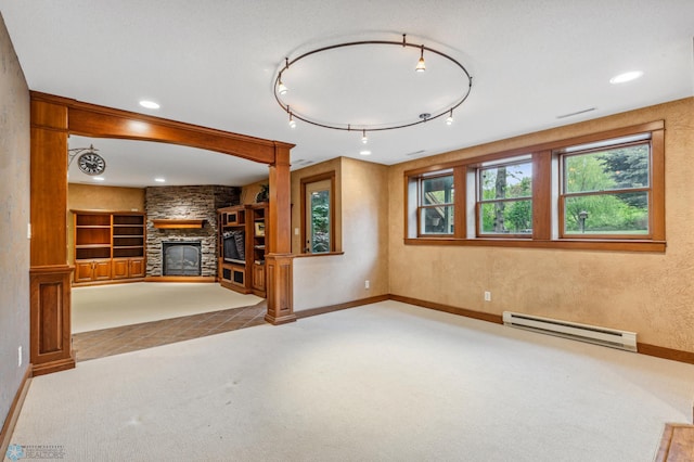 unfurnished living room featuring a baseboard heating unit, built in shelves, carpet, and a stone fireplace