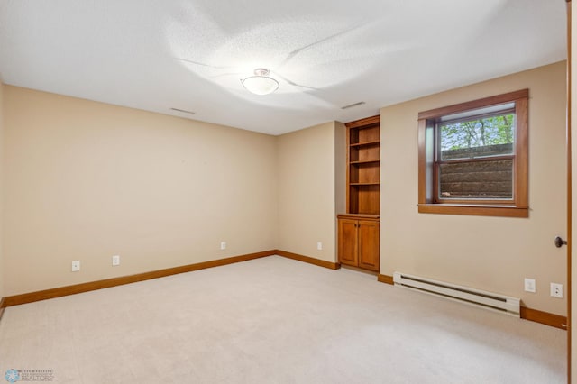 unfurnished room featuring a textured ceiling, baseboard heating, carpet, and built in features